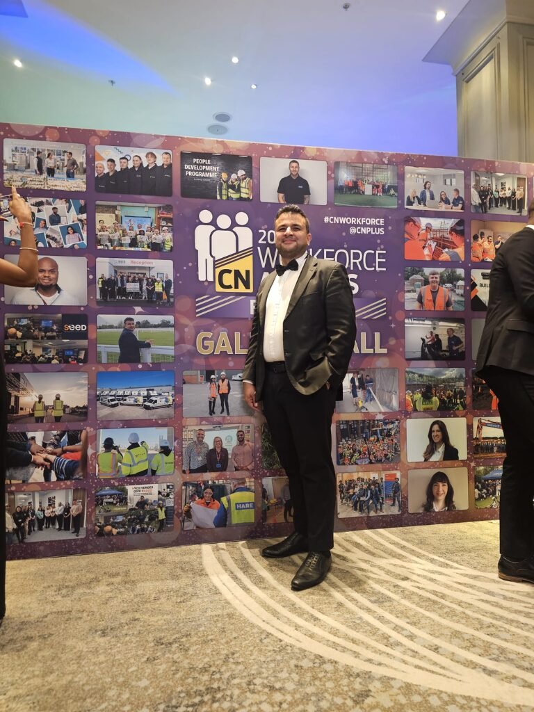 Sultan Qureshi standing at the CN Workforce Awards 2024 event after winning the Mentor of the Year award, dressed in a tuxedo with a vibrant event backdrop.